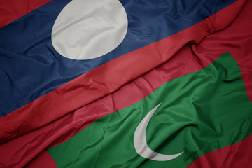 waving colorful flag of maldives and national flag of laos.