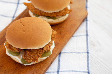 Homemade Burgers with fried chicken strips on a rustic wooden board, low angle view. Copy space.