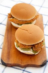 Homemade Burgers with fried chicken strips on a rustic wooden board, low angle view.