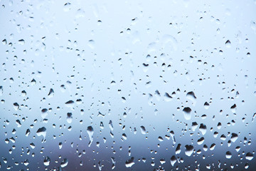rain droplets on glass over calm colorful background. business backdrop