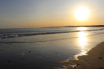 Watery sun on sea and sandy shore