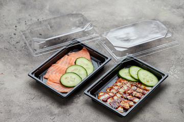 Fresh sliced salmon and smoked eel fillet with cucumber in plastic boxes ready for delivery. Wild atlantic fish