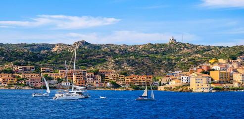 Fototapeta premium Panoramic view of La Maddalena old town quarter in Sardinia, Italy with port at the Tyrrhenian Sea coastline and island mountains interior in background