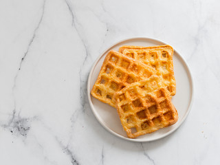 Delicious savory keto waffles. Two ingredients chaffles on plate over white marble background. Eggs and parmesan cheese low carb waffles. Top view or flat lay. Copy space left for text or design.