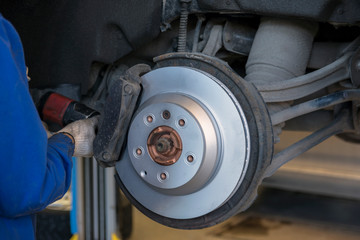 Car repair in a car service. Replacing brakes in a car service. New brake disc close up.