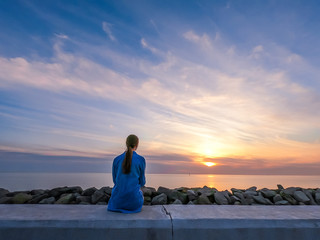 Silhouette of a woman in the blue shirt on the pink sunset background