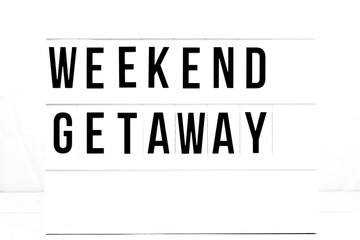 Retro Weekend Getaway Quote Sign on Vintage board. Travel and lifestyle