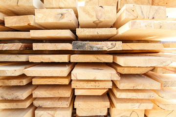 Stack of new wooden studs at the lumber yard. Timber on the construction site to dry. Background of sawed and processed wood of coniferous breeds.