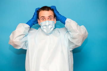 Portrait of scared man in protective suitt, medical mask and gloves against viruses and infections isolated on blue