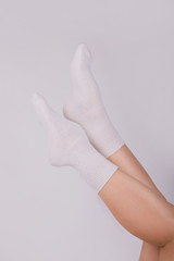 Female legs in white cotton patterned socks on white background. Ladies wearing sports socks