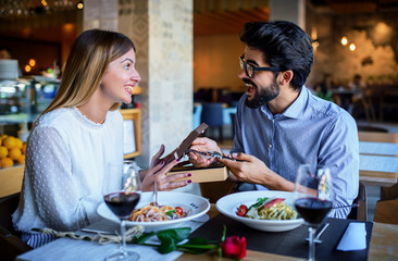 Young couple enjoying lunch in the cafe. Boyfriend got a watch as a birthday present from his girlfriend. Lifestyle, love, relationships concept