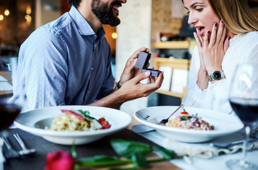 Young man surprised his girlfriend with engagement ring in the restaurant. Lifestyle, love, relationships, food concept