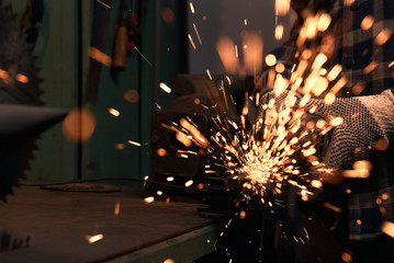 
Hands of a master cut an iron rod with an electric angle grinder