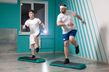 Fat man is very hardworking doing step-up exercises on steps during group fitness classes. Excess weight