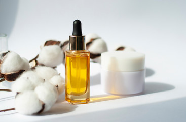 Yellow glass with dropper Bottle mockup cosmetic oil on white background with cotton branch Copy space. Beauty skin care