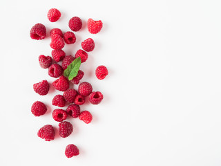 Heap of fresh ripe red raspberries with green leaf on white background. Raspberry with copy space for text or design. Top view or flat lay.