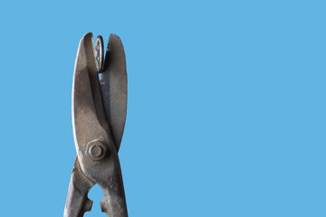 Old metal scissors cut a coin on a blue background