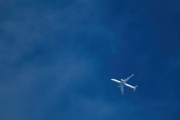 Ein weißes Flugzeug fliegt vor blauem Himme, 