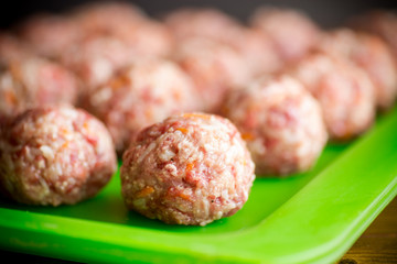 raw meatballs from beef and pork with carrots and rice