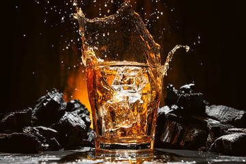 ice falls into a glass with expensive whiskey and spray flies in different directions