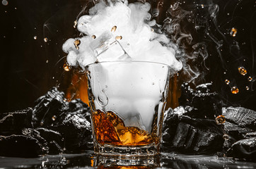 ice falls into a glass with a carbon dioxide cocktail and smoke forms