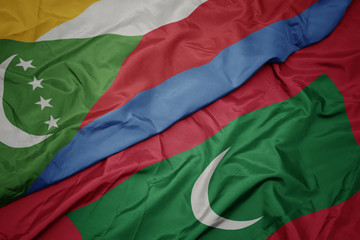 waving colorful flag of maldives and national flag of comoros.