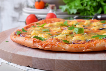 Round pizza with anchovies, mozzarella cheese and tomato sauce garnished with fresh parsley on white table