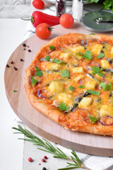 Round pizza with anchovies, mozzarella cheese and tomato sauce garnished with fresh parsley on white table