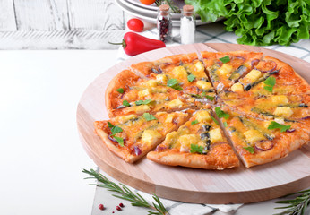 Round pizza with anchovies, mozzarella cheese and tomato sauce garnished with fresh parsley on white table