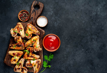 Grilled chicken wings in barbecue sauce on a wooden board on a concrete table with copy space for your text.