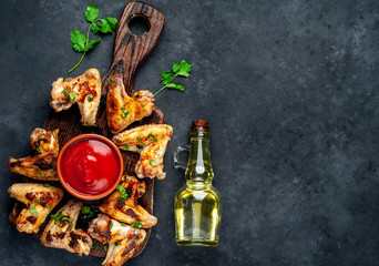 Grilled chicken wings in barbecue sauce on a wooden board on a concrete table with copy space for your text.