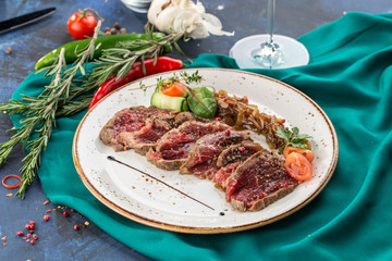 slices of roast beef with pickled onion with glass of red wine on blue background