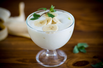 Homemade sweet yogurt with slices of ripe banana in a glass bowl
