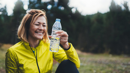 Happy sport girl laughing quenches thirst after fitness. Smile person drinking water from plastic...