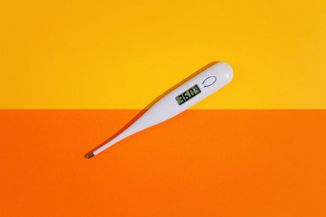Digital thermometer on top of colorful background. View from above.