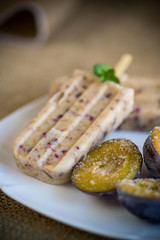 plum sweet homemade ice cream on a stick with slices of plum inside, in a plate