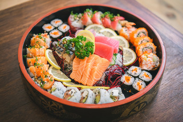 Mixed Sushi Set nigiri, rolls and sashimi served in traditional Japan black Sushioke round plate.