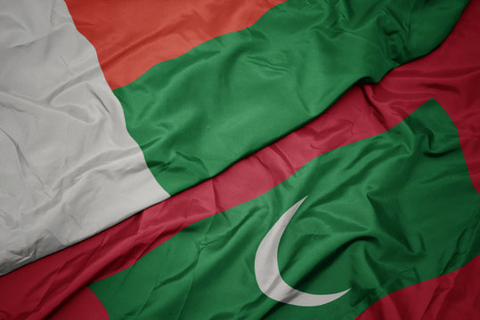 waving colorful flag of maldives and national flag of madagascar.