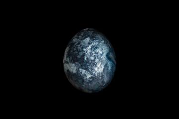 Painted egg looks like a planet isolated on a black background. Save earth concept