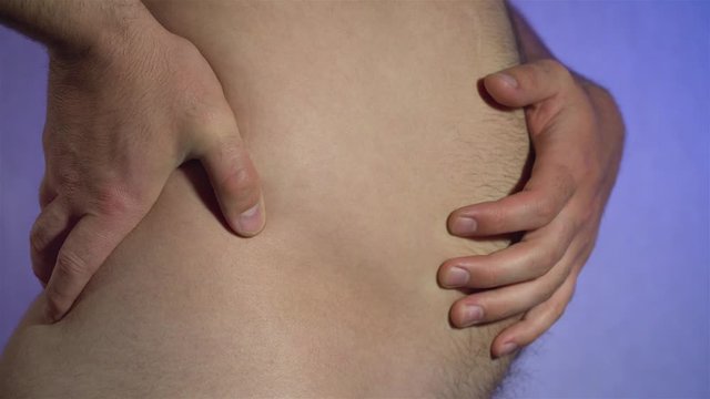 Man slaps his large hairy belly with initial stage of obesity using palm of hand. Unhealthy lifestyle and nutrition