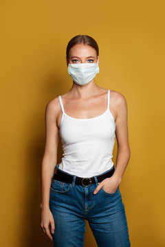 Woman Wearing Medical Mask Standing On Vibrant Yellow Background