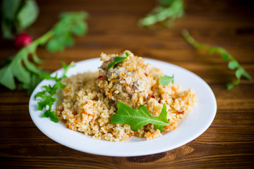 boiled bulgur groats with vegetables and meatballs in a plate
