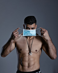 Male bodybuilder in a medical mask stands torso.