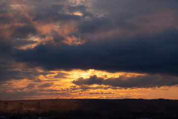 Fototapeta premium Dramatic sunset. Contrast sunshine rays to dark cloud.