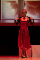 Dancer in a red dress dancing Spanish flamenco on the stage in the theater