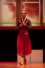 Dancer in a red dress dancing Spanish flamenco on the stage in the theater
