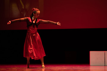 Dancer in a red dress dancing Spanish flamenco on the stage in the theater