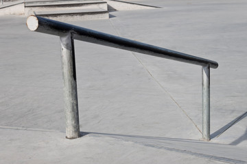Sloped metal rail for grind tricks in an empty concrete skatepark