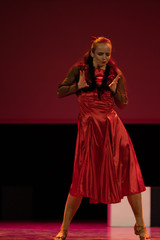 Dancer in a red dress dancing Spanish flamenco on the stage in the theater