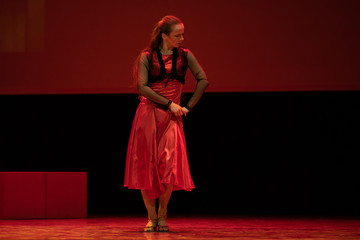 Dancer in a red dress dancing Spanish flamenco on the stage in the theater